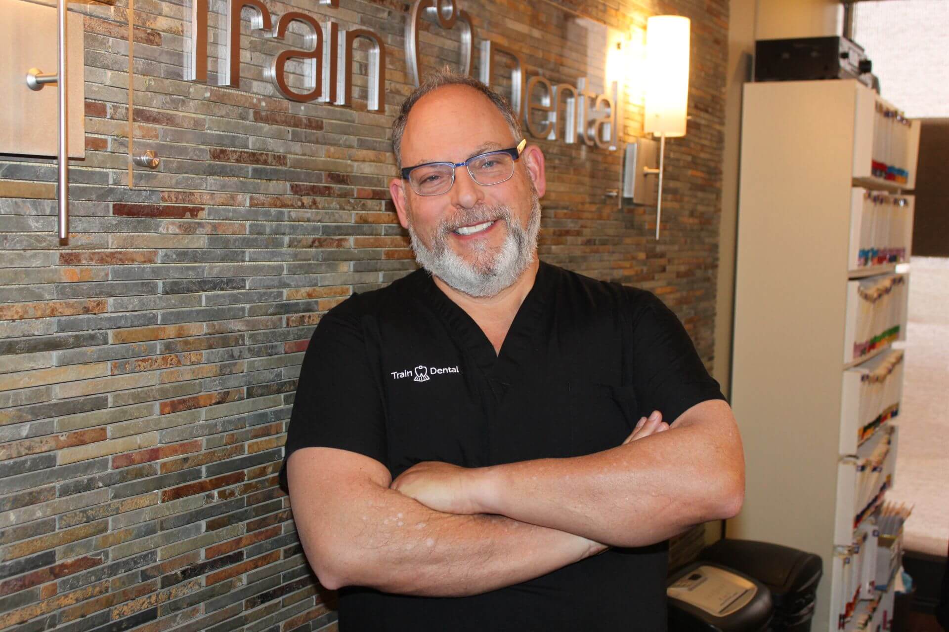 Dr. Marshall Train with arms crossed and smiling in clinic